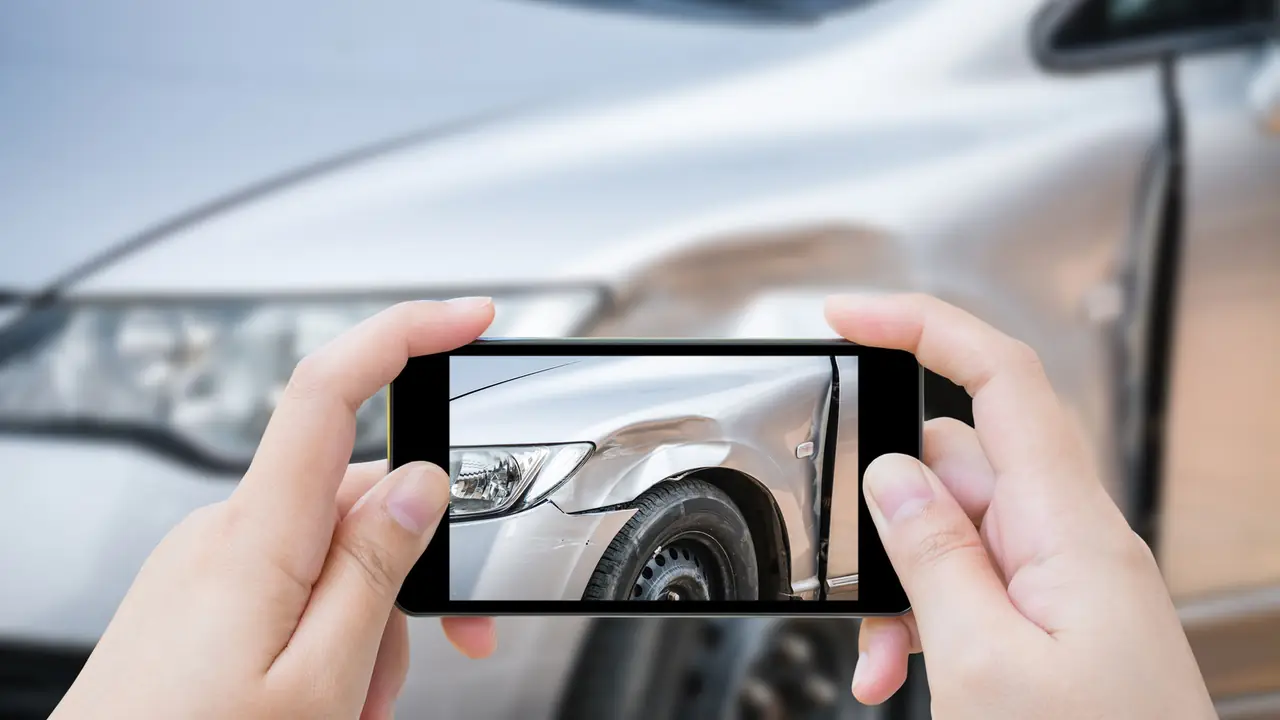 Schaden an einer Autotür wird mit dem Handy fotografiert